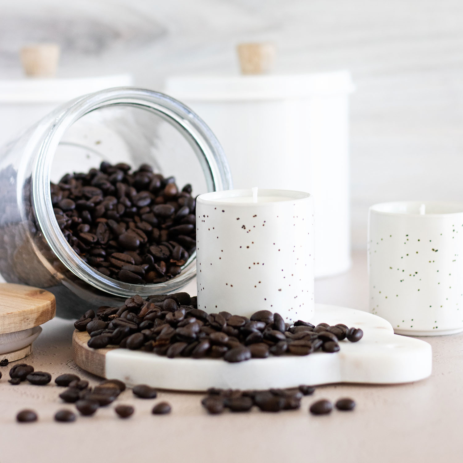 large jar of coffee beans spilling over DIY coffee candles in espresso cups on a counter in a coffee bar